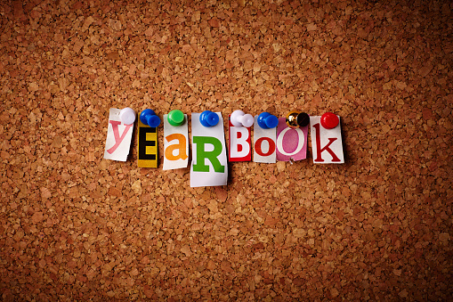 Cork board with cutout letters spelling yearbook arranged with push pins