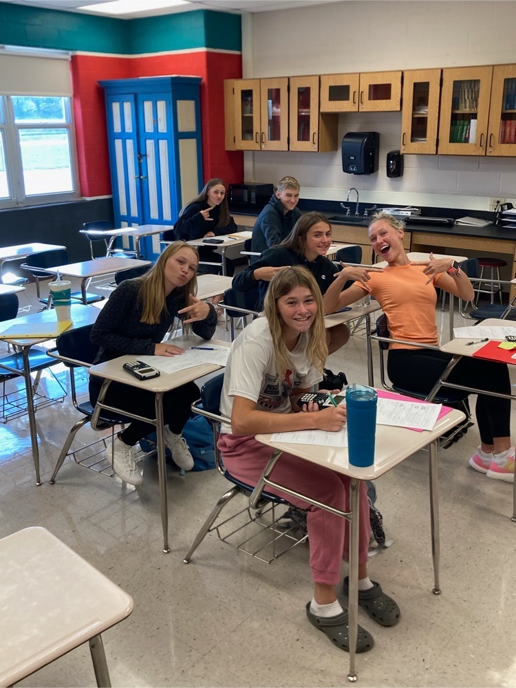 students seated in desks with thumbs up while working on Algebra equations