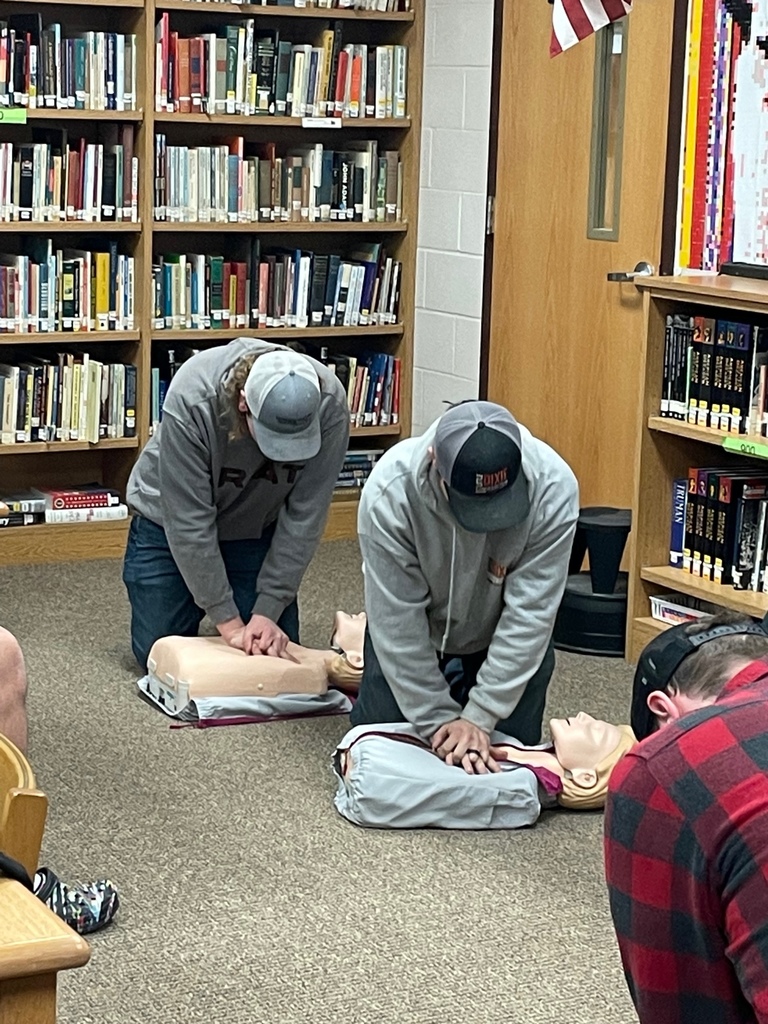 Students practice CPR on training  dummy in library floor
