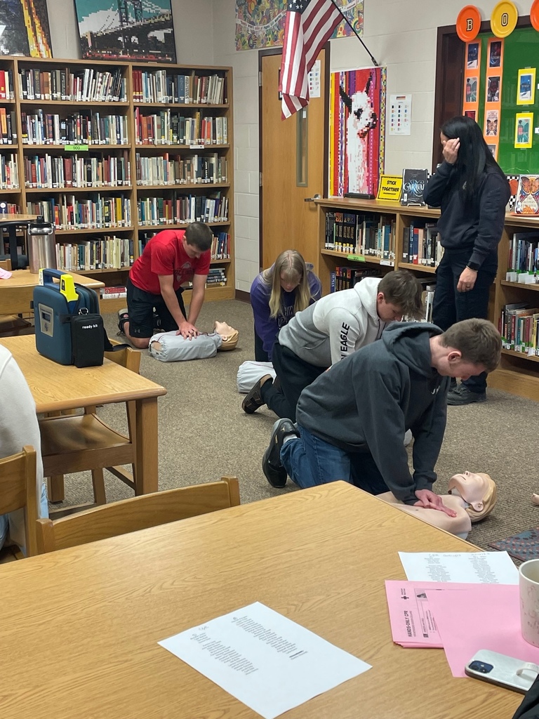 Students practicing CPR on training dummies while Kaila Pollard observes
