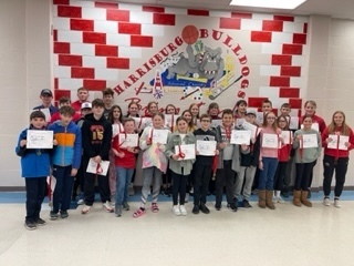 Students standing in front of Harrisburg Bulldogs mural with their Advanced score certificates
